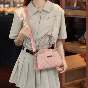 Detailed close-up of pink quilted faux leather handbag with adjustable fabric shoulder strap