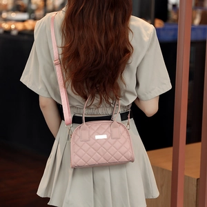 Detail of pink quilted crossbody bag with adjustable strap and gold metal hardware