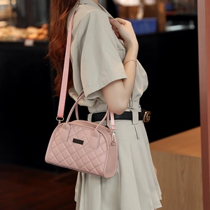 Detailed view of pink quilted handbag with wide shoulder strap worn by a model