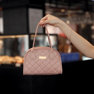 Close-up of light pink quilted handbag with dual handles and elegant metal hardware details