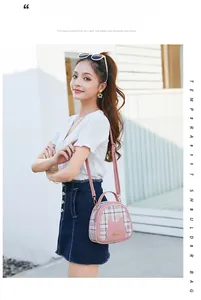 Detailed view of cat-ear plaid handbag featuring pink contrast and gold hardware accents