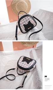 Detail view of plaid shell bag with cat pattern patch and golden metal logo plaque