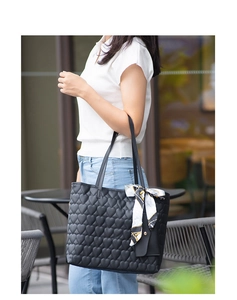 Detail of black heart-quilted tote bag featuring a decorative printed silk scarf and mini pouch