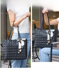 Detail of black heart quilted tote bag with decorative geometric silk scarf handle