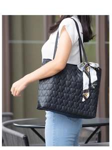 Close-up of heart quilted pattern on black PU leather tote bag with printed silk scarf