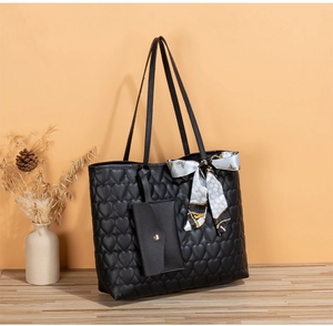 Close-up of black tote bag with heart-shaped quilting and decorative blue silk scarf