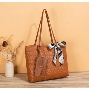 Close-up of caramel quilted heart pattern tote bag with printed silk scarf and mini pouch
