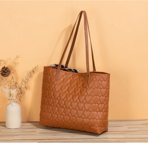 Brown tote bag with heart quilting and printed silk scarf detail on wood surface
