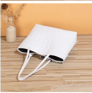 Detailed view of white heart-quilted tote bag with stylish silk scarf accessory