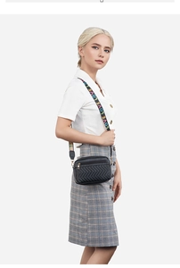 Detail of black quilted crossbody bag featuring colorful LOVE embroidered wide strap