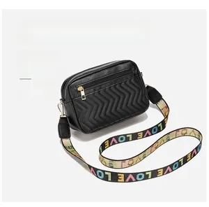 Detail of black quilted crossbody bag featuring wave stitching and chic wide jacquard strap