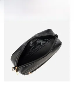 Detail view of black pebble leather crossbody bag with gold zipper and inner compartment