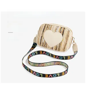Detailed close-up of woven beige crossbody bag with yellow heart patch and wide strap