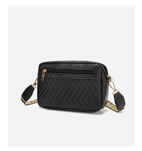 Detail of black quilted camera bag with V-shaped stitching and colorful woven strap