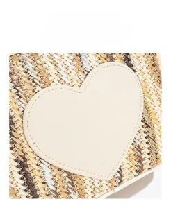Close-up of heart leather patch on multi-color woven straw bag with stitching