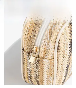 Macro detail of straw woven bag showing side texture, leather trim and gold zipper