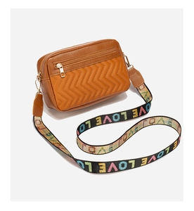 Detail of caramel brown crossbody bag with V-shaped quilting and LOVE patterned strap