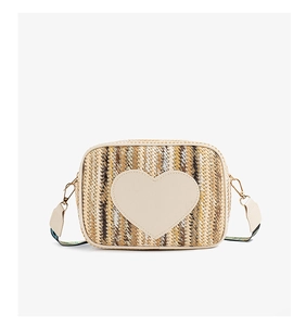 Close-up of heart-shaped patch on striped straw bag with colorful woven shoulder strap