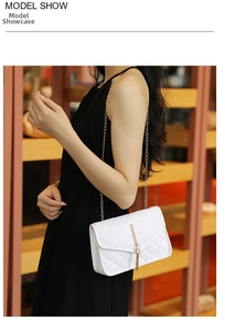 White quilted crossbody bag with gold tassel detail and chain strap shown on model