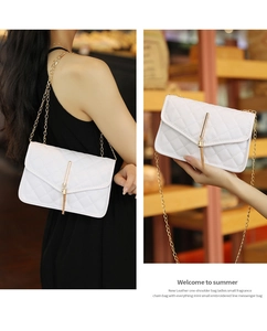 Detail of white quilted crossbody bag with golden chain and tassel pendant on a strap