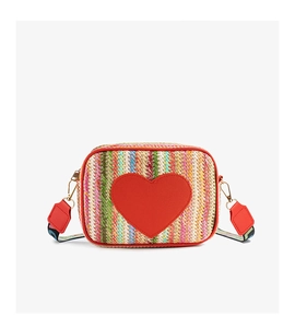 Detail of colorful woven straw camera bag with red heart patch and geometric strap