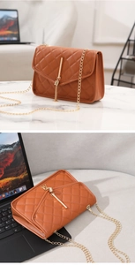 Detail of caramel quilted crossbody bag with gold hardware and tassel on marble surface