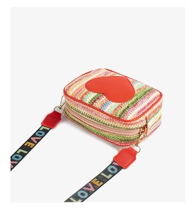 Detail of woven square phone bag featuring a red heart patch and a colorful LOVE strap