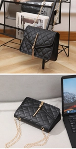 Close-up of black quilted shoulder bag with gold chain strap and metal tassel detail