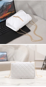 Detail view of a white quilted crossbody bag with gold chain strap on an office desk