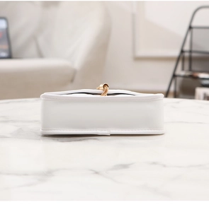 Detail view of white quilted crossbody bag with precise stitching and gold tassel