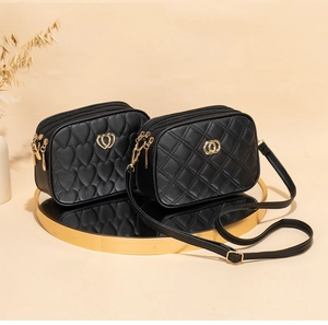 Detail of black quilted leather handbags with golden zippers on a mirror tray display