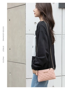 Détail du sac à bandoulière matelassé rose avec chaîne dorée et logo sur fond de rue
