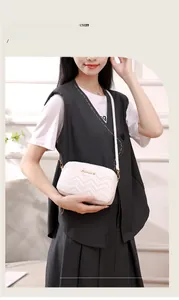 White camera bag with chevron quilting and gold logo worn by model as a crossbody purse
