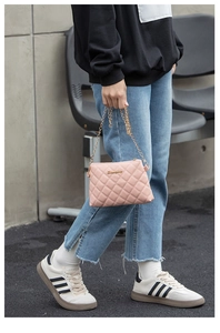 Détail d'un sac bandoulière matelassé rose avec chaîne dorée et logo en métal brillant