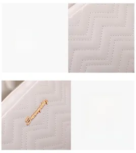 Close-up of white camera bag featuring V-shaped quilted faux leather and gold logo