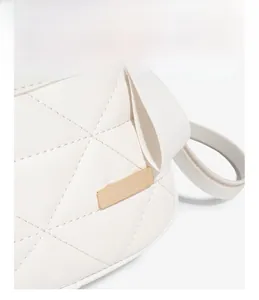 Détail d'un sac en cuir blanc matelassé avec plaque métallique dorée et zip fluide