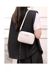 Close-up of white wave-quilted camera bag with gold hardware and logo on a model