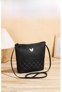 Détail d'un sac bandoulière matelassé noir avec logo papillon en métal argenté
