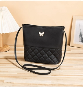 Gros plan d'un sac à bandoulière noir matelassé avec boucle papillon et fine bandoulière