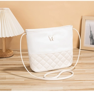 Détail du matelassage et du papillon en métal sur le sac à bandoulière crème