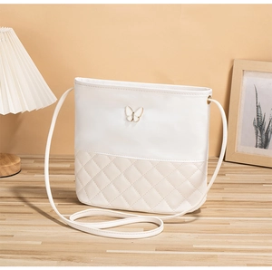 Détail du motif matelassé et du logo papillon sur le sac à bandoulière blanc