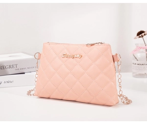 Détail du sac bandoulière matelassé rose avec logo doré et chaîne élégante