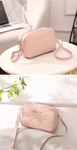 Detail of pink quilted crossbody bag with wave stitching and gold metal logo accent