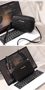 Close-up of black quilted camera bag with V-shaped stitching and golden metal logo