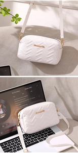 Close-up of white quilted camera bag with V-shaped texture and gold metal logo detail