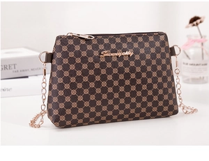 Détail du motif trèfle et de la chaîne dorée sur un sac à bandoulière marron
