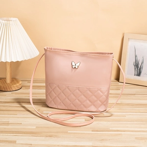 Sac à bandoulière rose matelassé avec détail papillon sur une table en bois chic