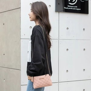 Sac à bandoulière rose matelassé avec chaîne dorée porté par un mannequin de profil