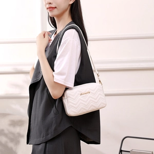 White wavy quilted crossbody bag with gold logo and adjustable shoulder strap for women