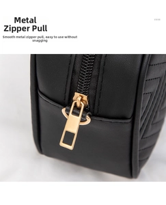 Close-up of golden zipper puller and V-shaped quilted stitching on black leather bag
